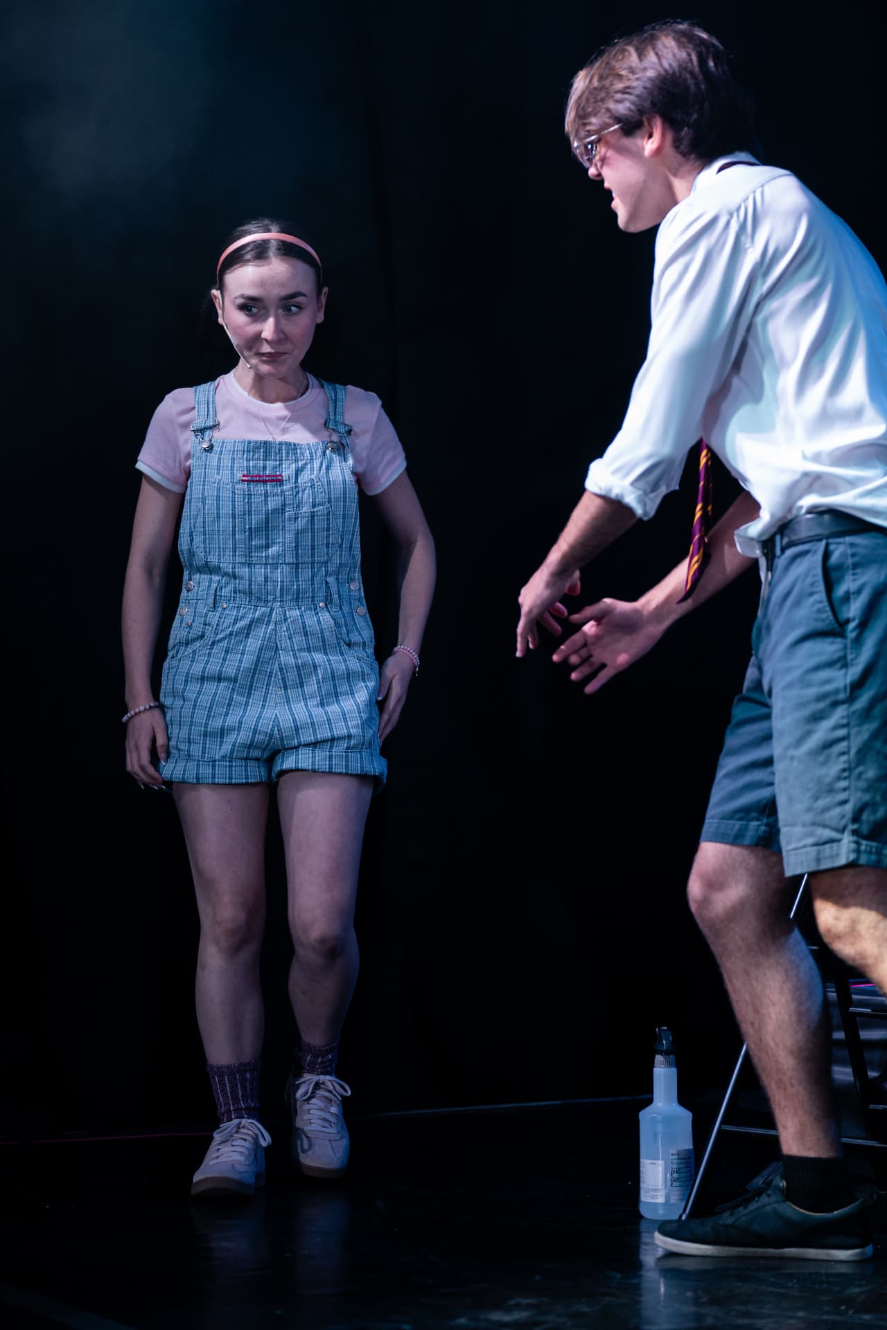 Richard Jordan leaning in to coach a fellow speller on stage during Putnam County Spelling Bee