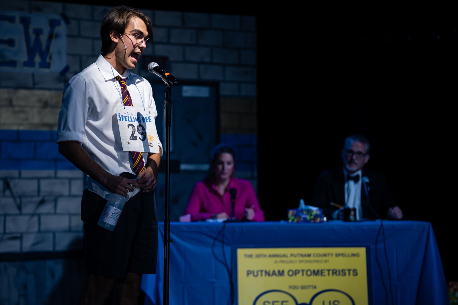 Richard Jordan at the microphone holding his spray bottle as the judges watch