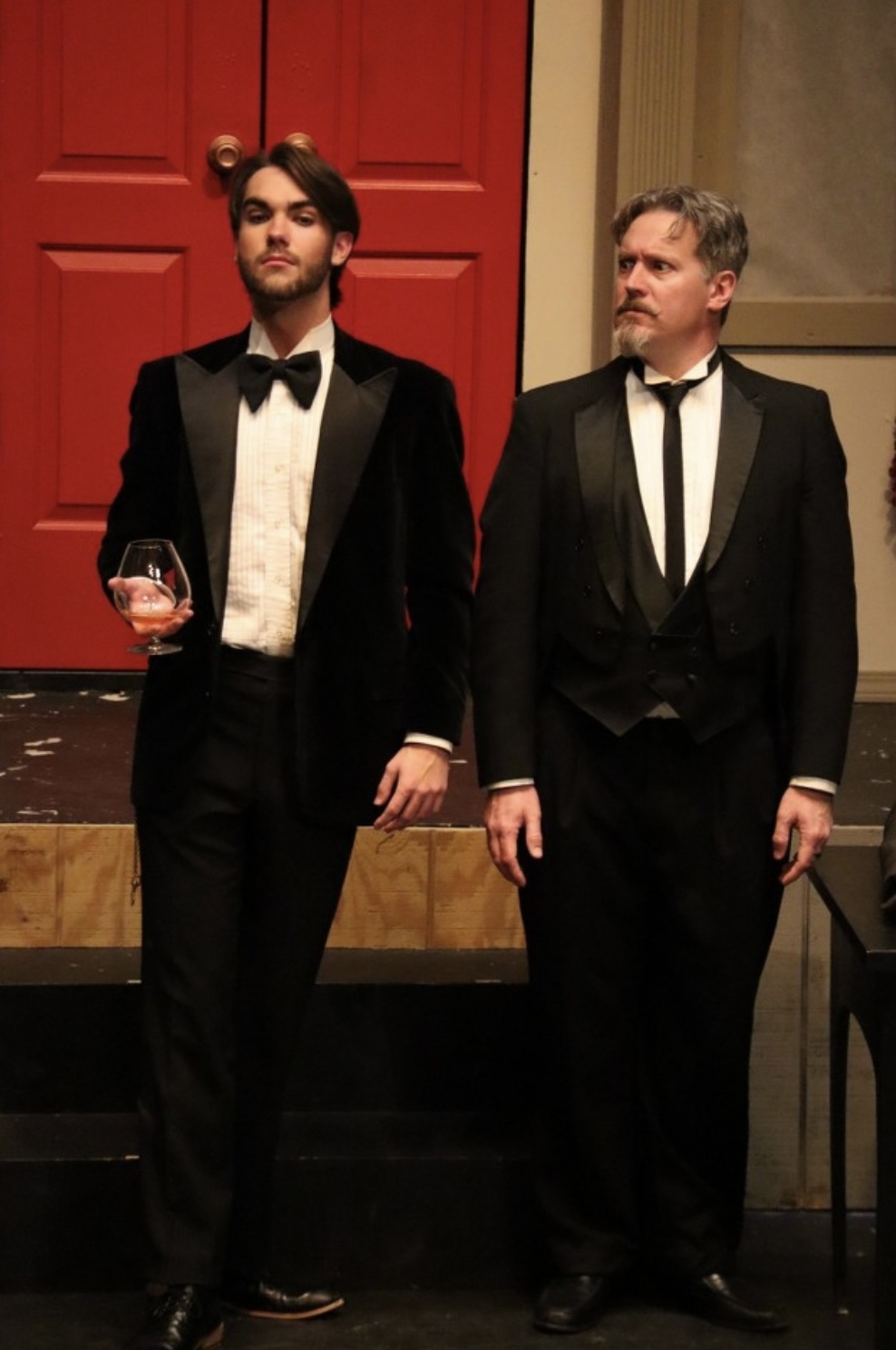 Richard Jordan standing in a tuxedo before the red doors in CLUE