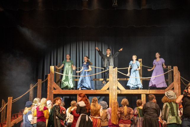 Richard Jordan center stage with the ensemble in a period musical