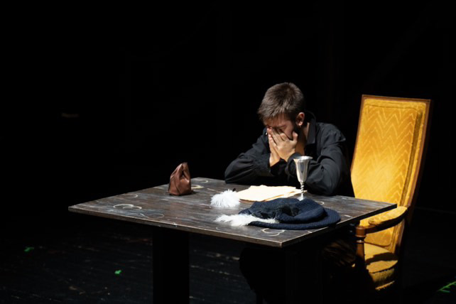 Richard Jordan seated at a table in a dimly lit dramatic scene