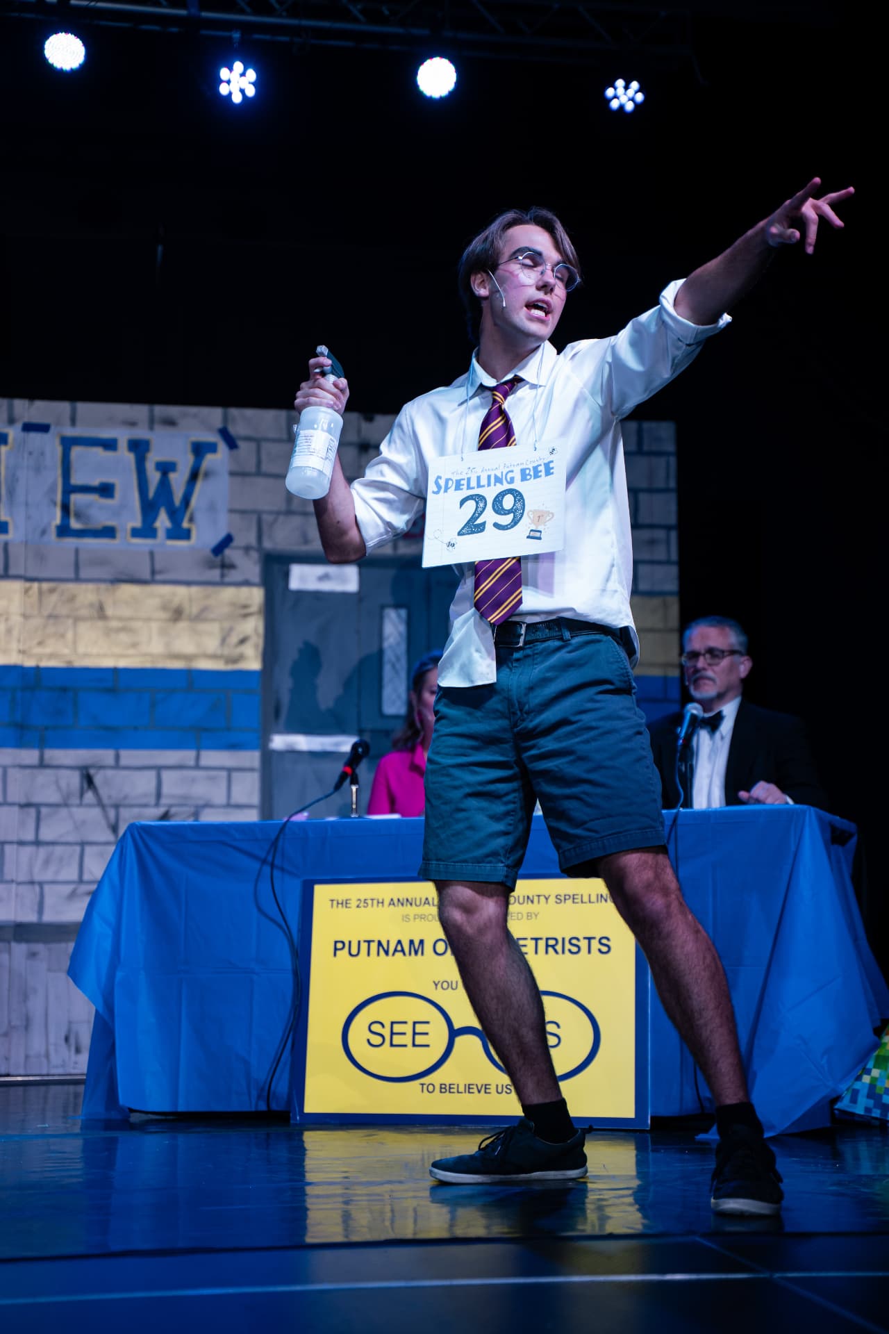 Richard Jordan striking a dramatic pose with his spray bottle raised and arm outstretched during Putnam County Spelling Bee