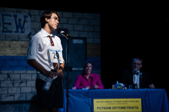 Richard Jordan at the microphone addressing the judges' table in Putnam County Spelling Bee