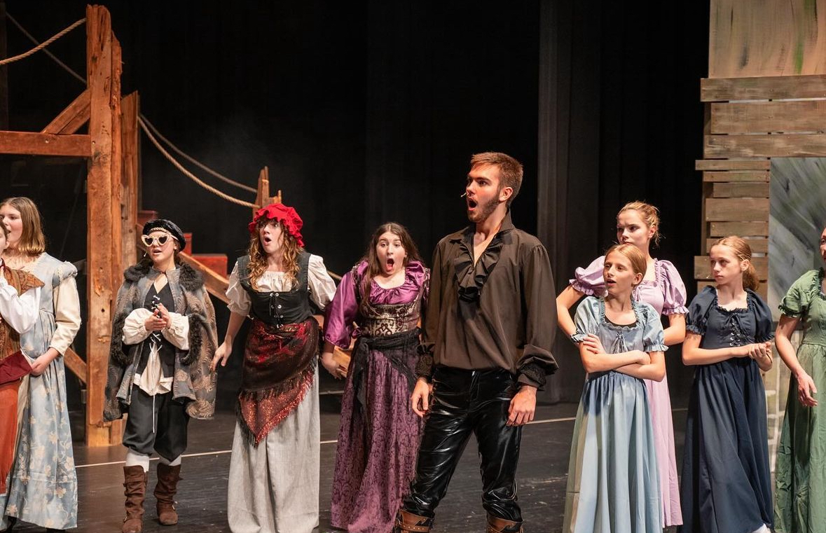 Richard Jordan singing with the ensemble in a period musical