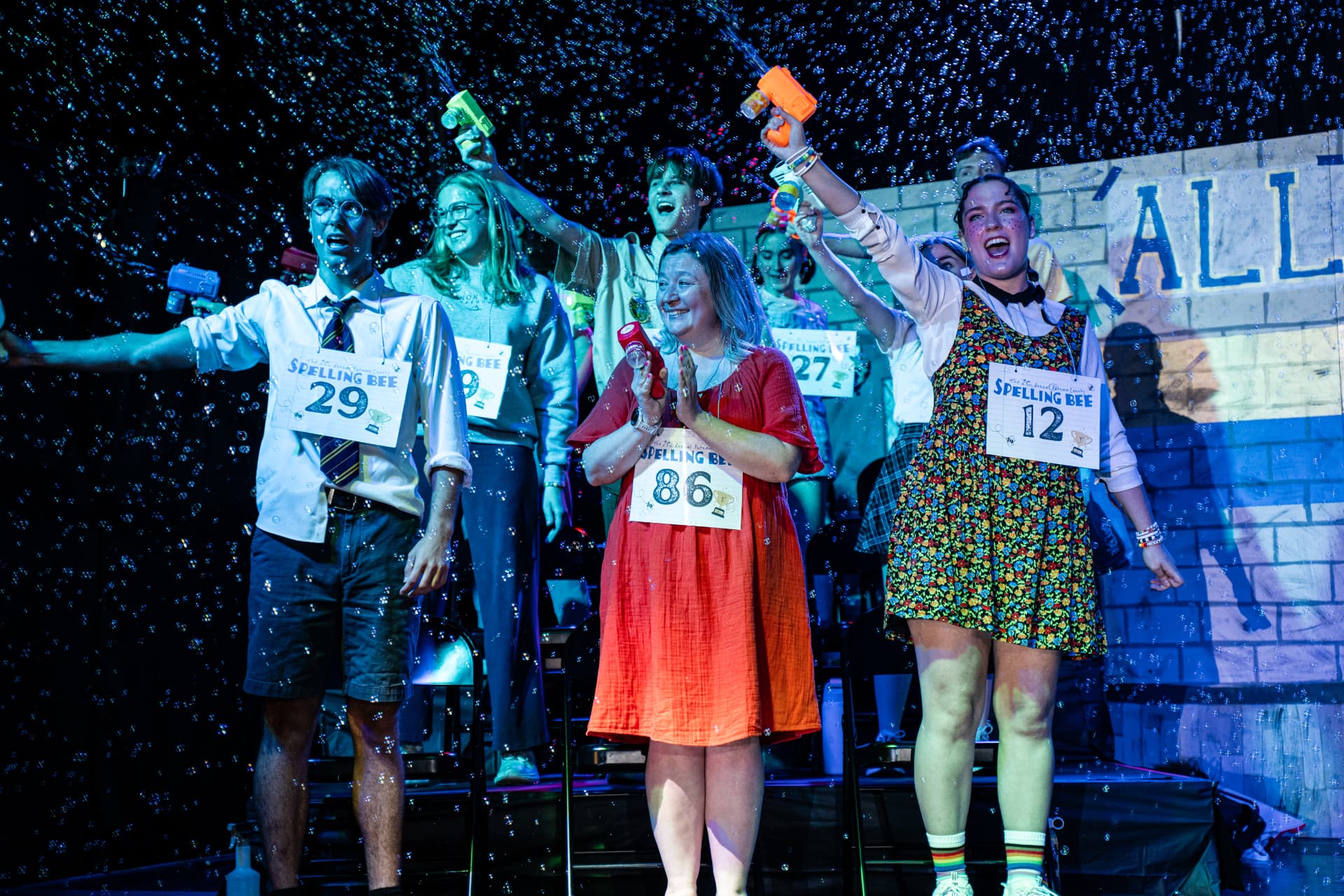 The full Spelling Bee cast celebrating with bubble guns in the ensemble finale